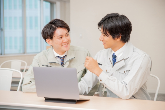 作業服を着た男性二人が談笑する様子